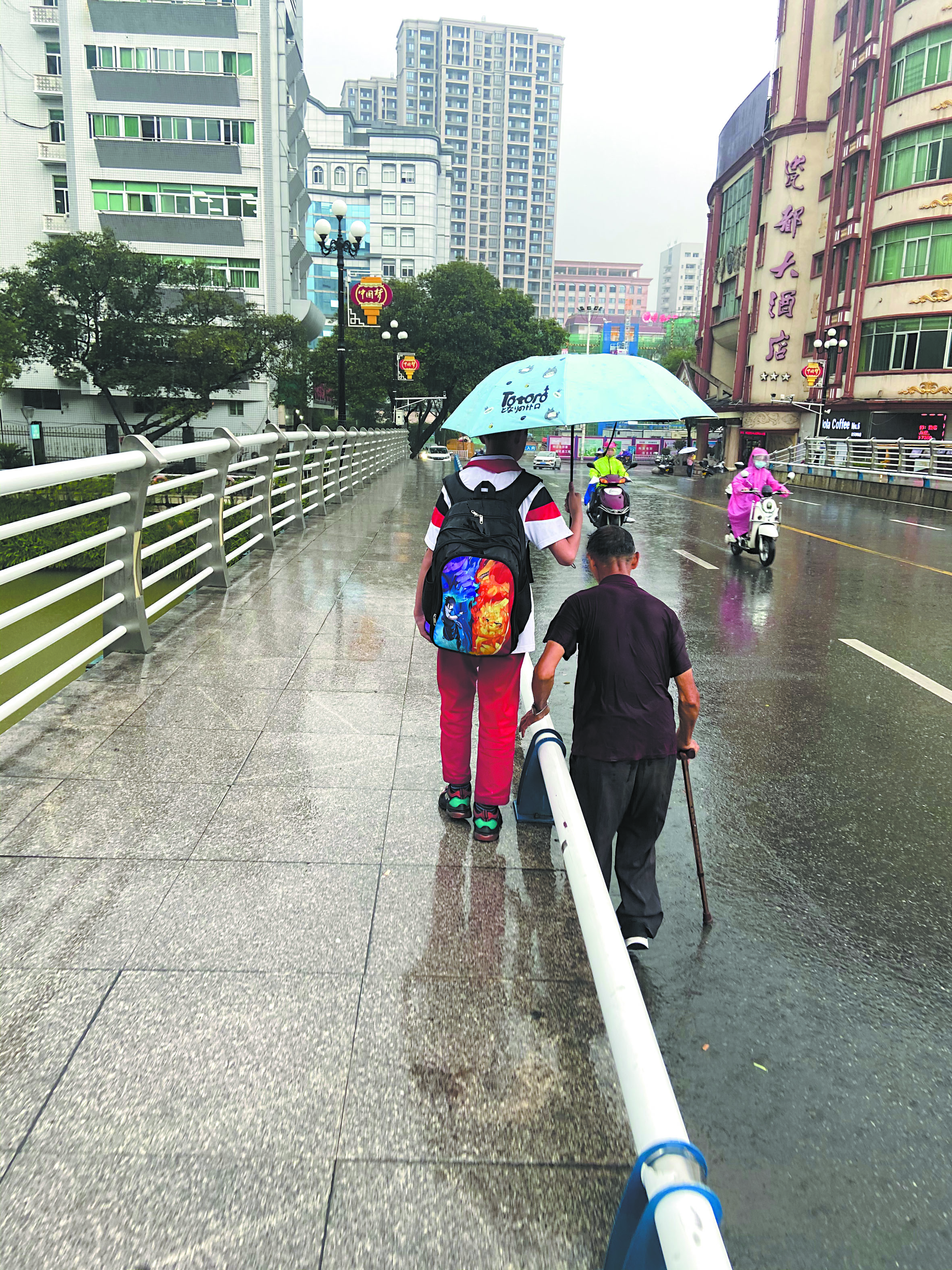 吴正杰为老人遮雨（读者供图）.jpg